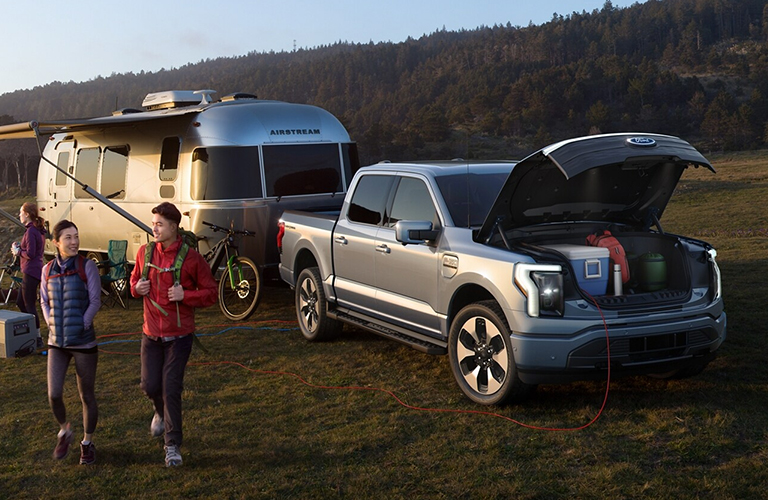 2022 Ford F-150 Lightning truck front view with people and trailer